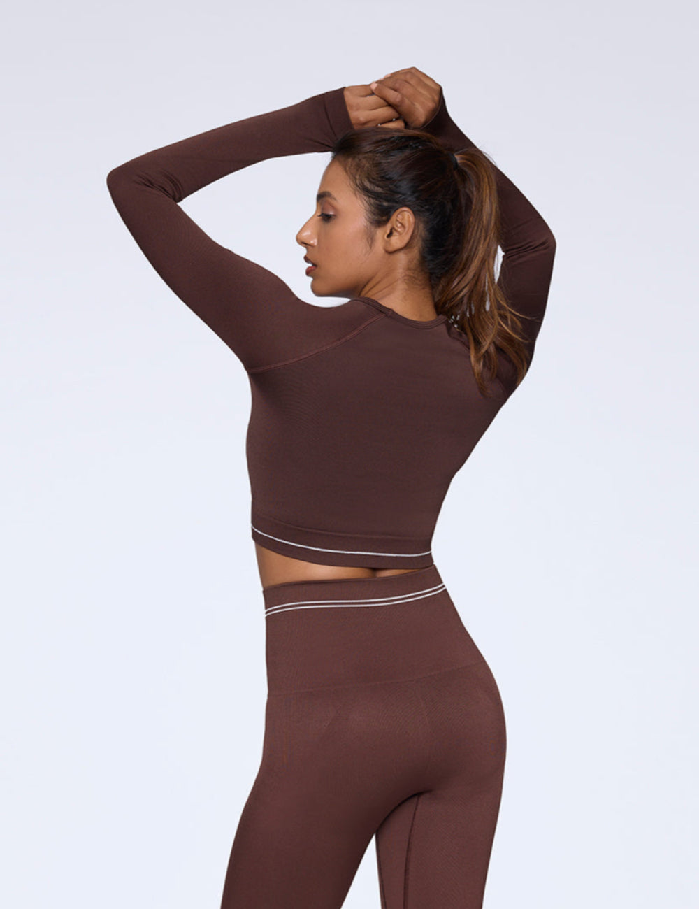 Woman wearing a brown athletic outfit on a white background