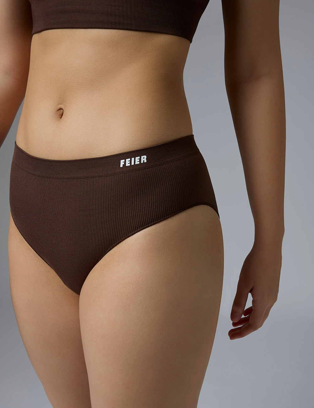 This image features the Airwave Bikini, a pair of high-rise, ribbed panties designed for optimal comfort and minimal chafe. The panties are crafted with a smooth, seamless look in a lush brown color, highlighted by the brand's logo on the waistband.