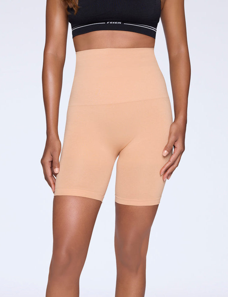 Woman wearing shapewear shorts on a light background