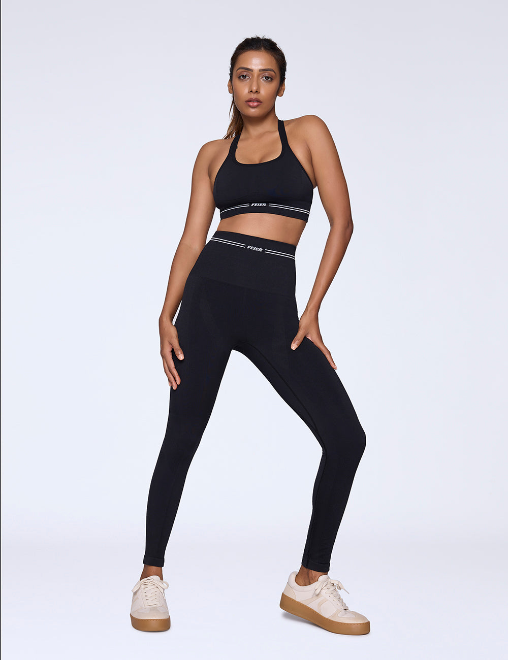 Woman wearing a black sports bra and leggings set on a white background