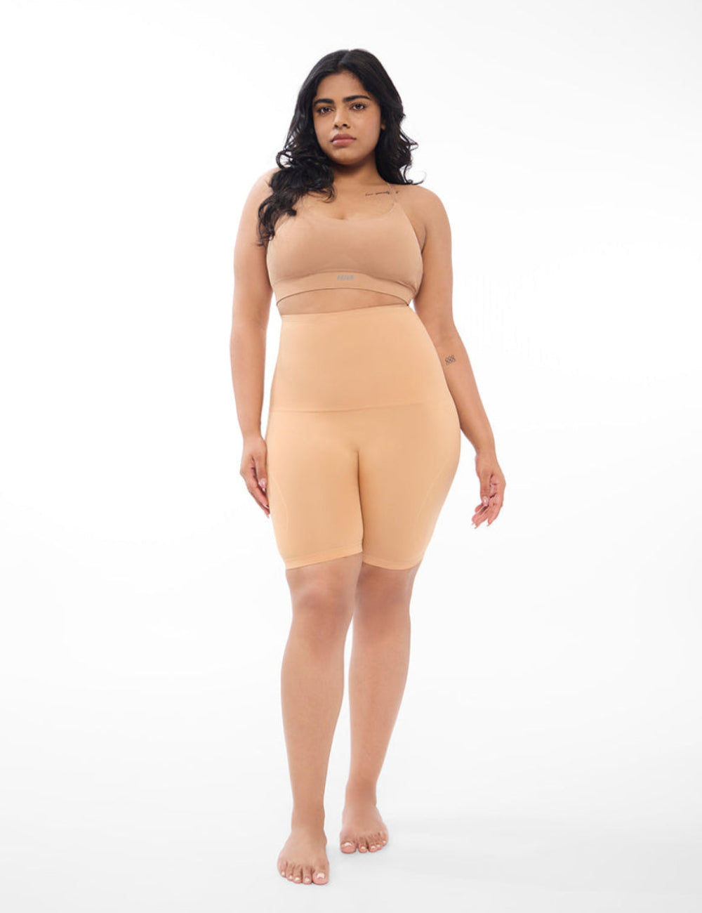 Woman wearing a beige shapewear dress on a white background